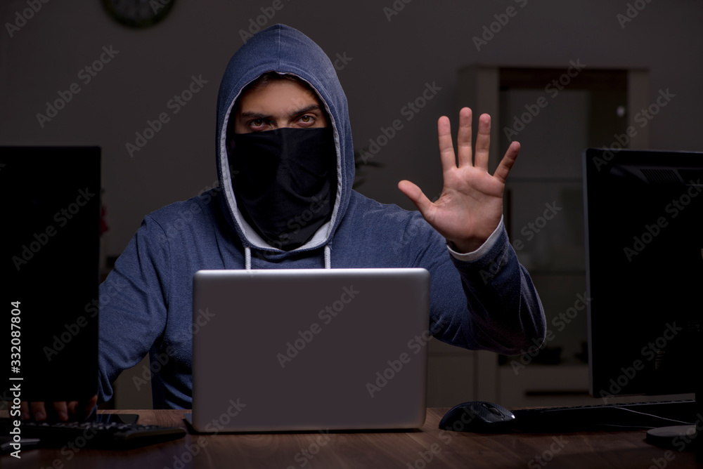 Male hacker hacking security firewall late in office Male hacker hacking security firewall late in office