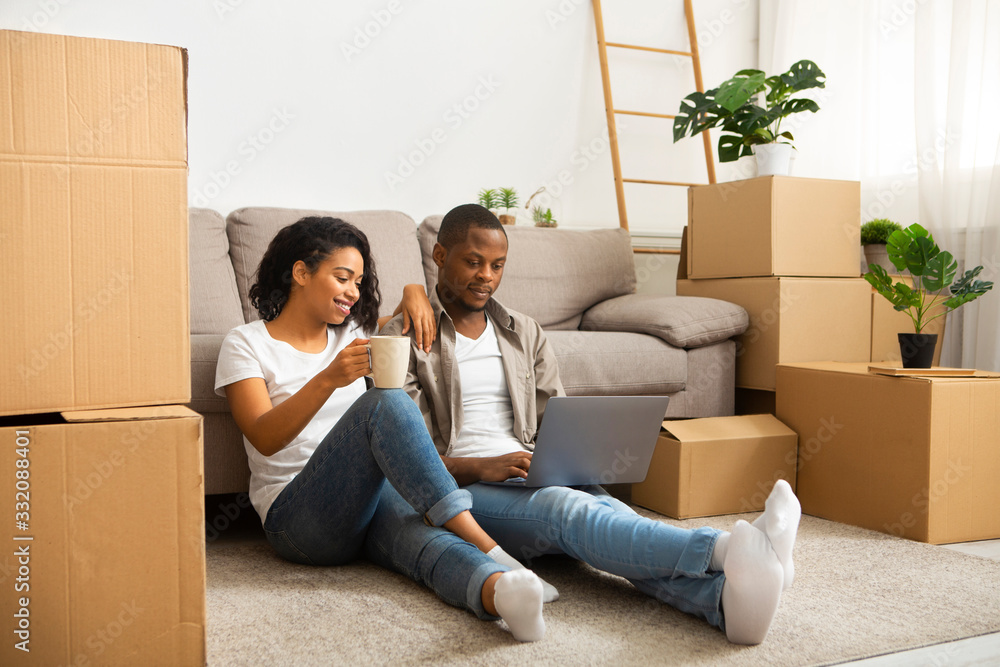African american couple sitting on the floor looking at laptop African american couple sitting on the floor looking at laptop