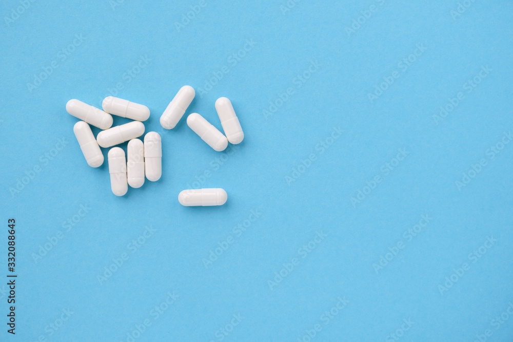 White pills lying on a blue paper background. Concept of pharmacy