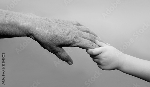 hand of a young baby touching old hand of the elderly