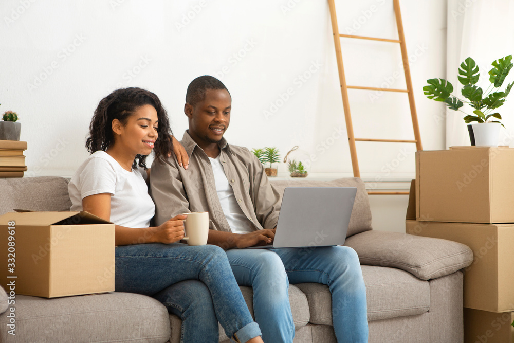 Couple searching for ideas sitting on sofa with boxes Couple searching for ideas sitting on sofa with boxes