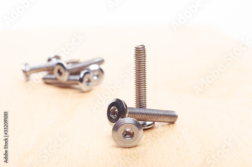 small bunch of hex head bolt screws on wooden table. Close up view photo