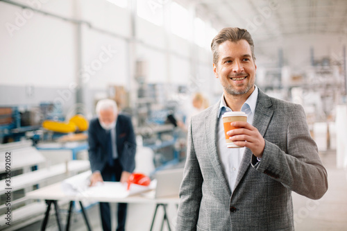 Young businessman drinking coffee at work. Handsome businessman in factory. 