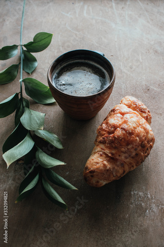 Cappuccino coffee and croissant on wooden background on the table. Perfect breakfast in the morning. Rustic candid style.