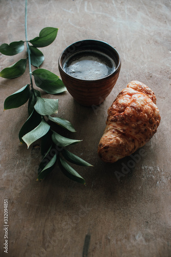 Cappuccino coffee and croissant on wooden background on the table. Perfect breakfast in the morning. Rustic candid style.