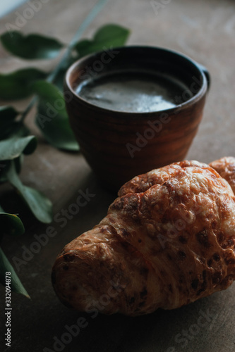 Cappuccino coffee and croissant on wooden background on the table. Perfect breakfast in the morning. Rustic candid style.