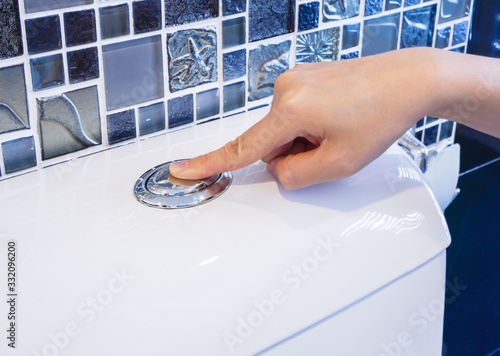 Foto Hand press index finger on toilet flush button ,selective focus on finger and dr