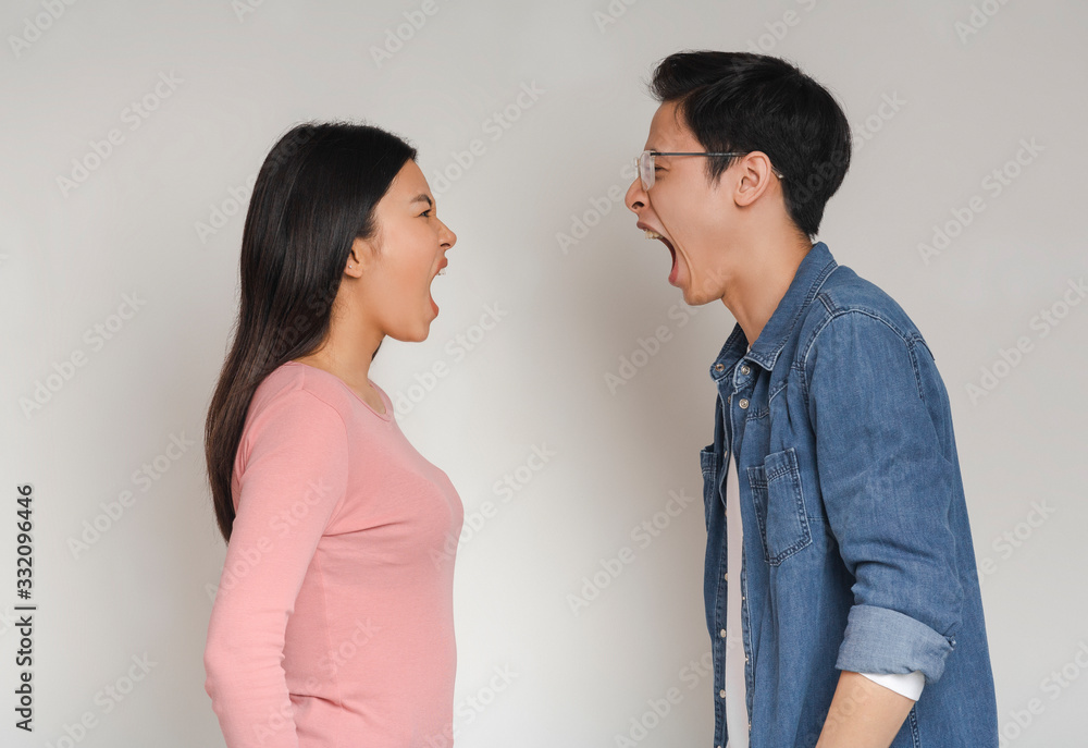 Asian man and woman shouting over grey background Asian man and woman shouting over grey background