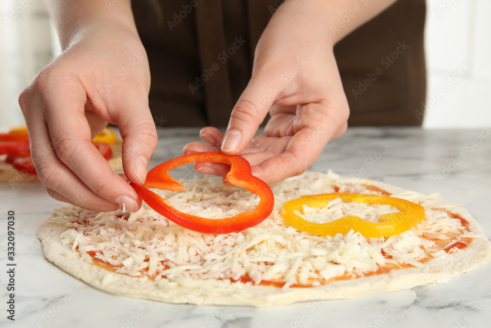 Woman adding bell pepper to pizza white marble table, closeup