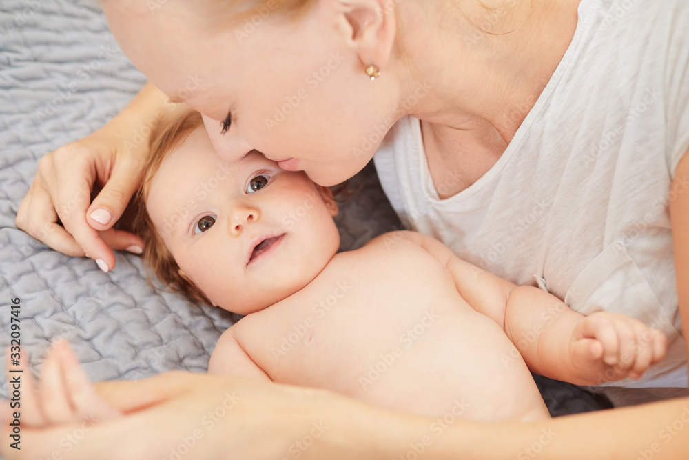 Mother hugging her baby lying on a bed Mother hugging her baby lying on a bed