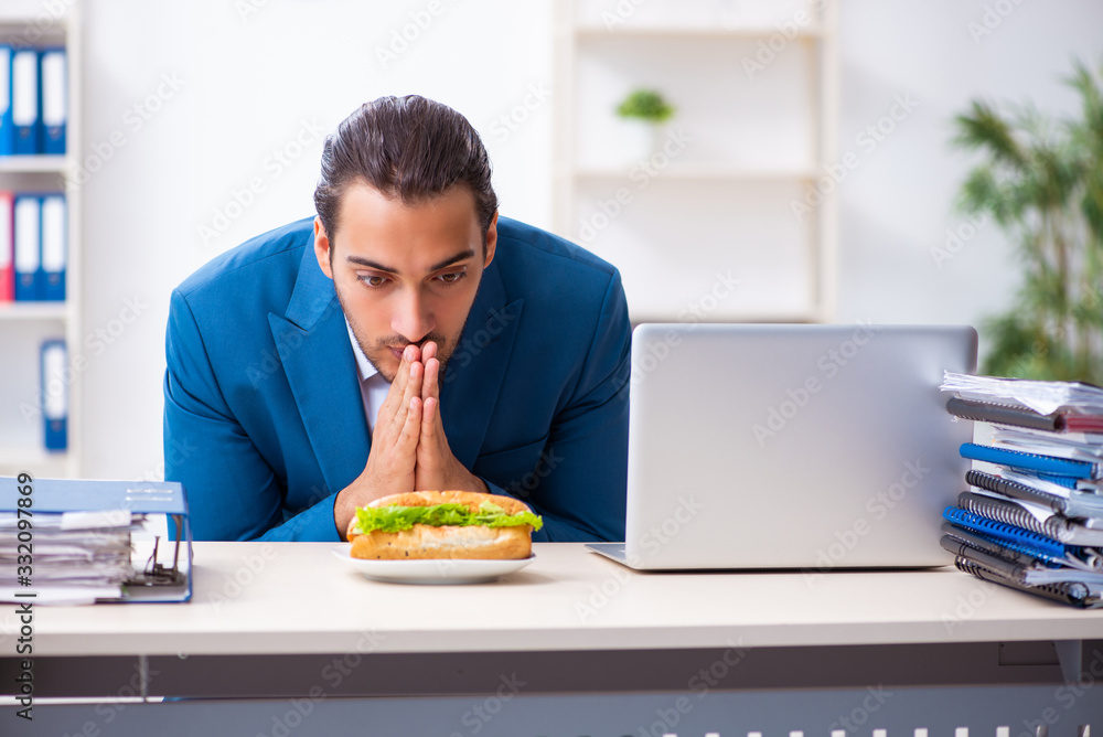 Young male employee having breakfast at workplace Young male employee having breakfast at workplace