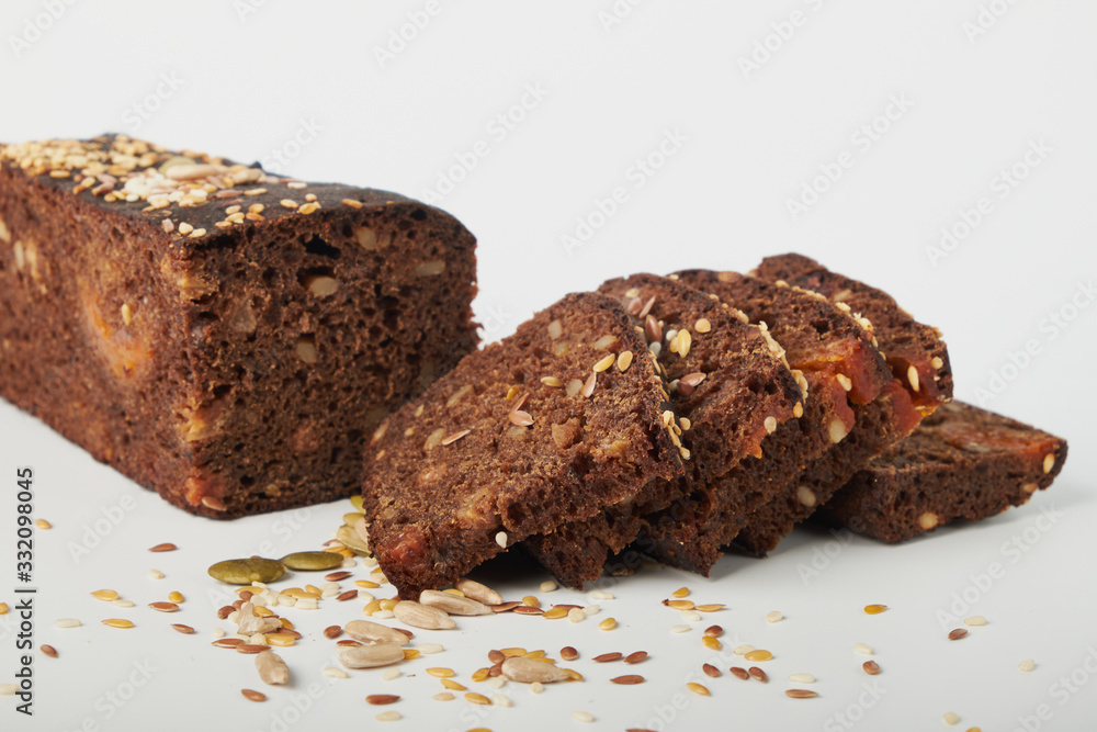 fresh bread with various seeds (pumpkin, dried apricots, flax, sunflower, sesame, prunes) is decorated with wheat ears isolated on a white background. fresh bread with various seeds (pumpkin, dried apricots, flax, sunflower, sesame, prunes) is decorated with wheat ears isolated on a white background.