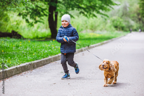 little kid with small brown dog running in city park