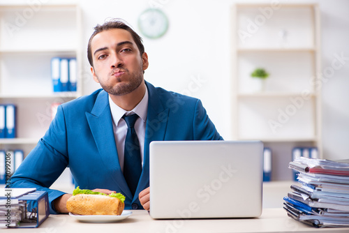 Young male employee having breakfast at workplace