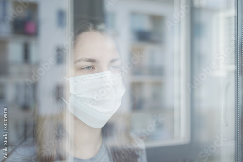 Young Woman in Quarantine Looking out the Window.