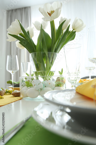 Festive table setting with Easter decorative eggs in bowl and white tulips