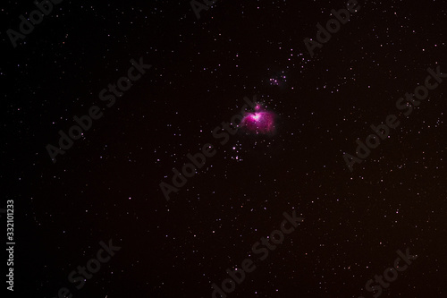 the pink Orion Nebula in the starry night sky