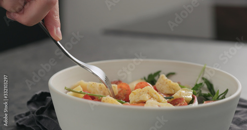 man eat salad with cherry tomatoes, mixed grens and cheese from white bowl photo