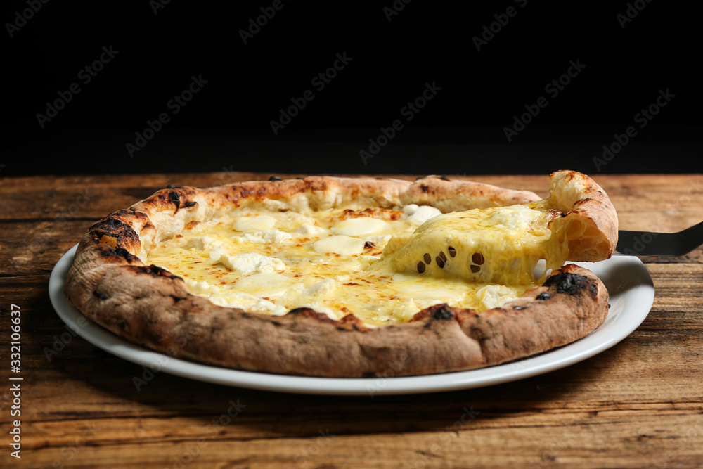 Taking slice of tasty cheese pizza on wooden table, closeup Taking slice of tasty cheese pizza on wooden table, closeup