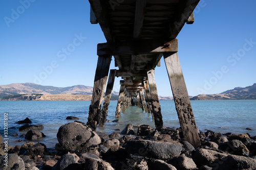 Under the wooden dock on the lake with black rock. © tonklafoto