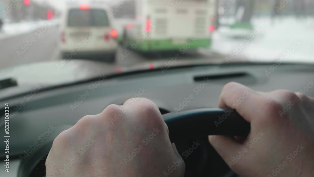 Close up of driver's hands on steering wheel. Blurred view of emergency car moving ahead in front of driver. View through windscreen. Close up of driver's hands on steering wheel. Blurred view of emergency car moving ahead in front of driver. View through windscreen.