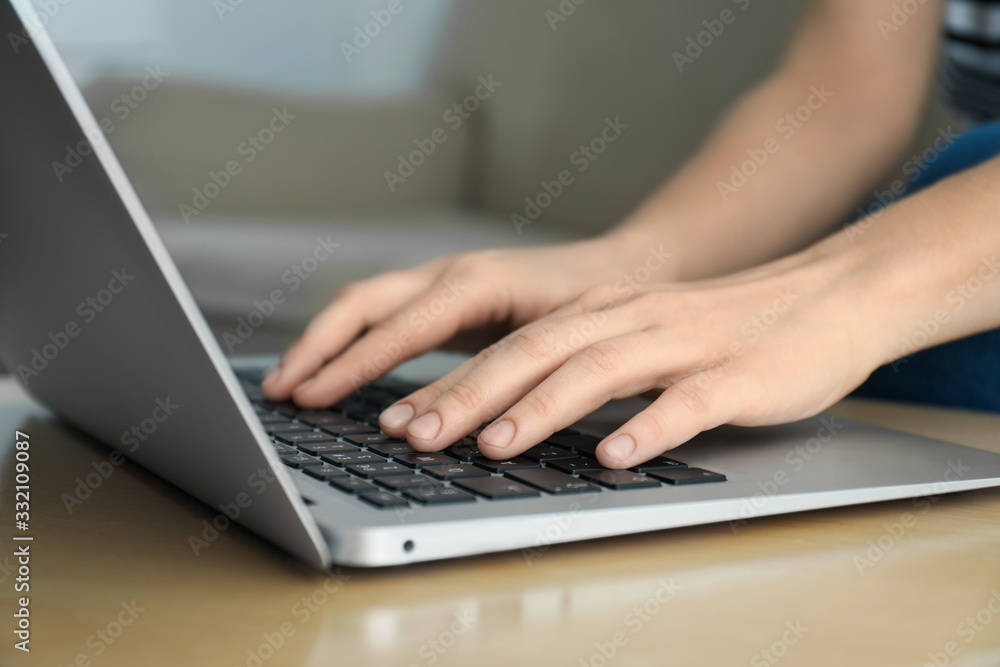 Woman working on modern laptop at wooden table indoors, closeup Woman working on modern laptop at wooden table indoors, closeup