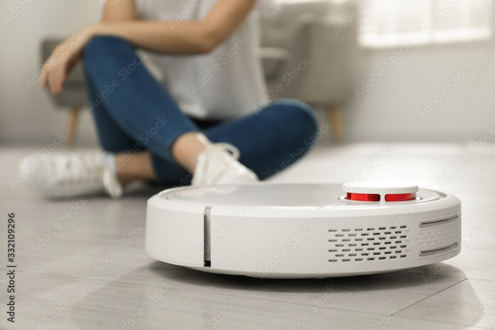 Fototapeta premium Woman using robotic vacuum cleaner at home