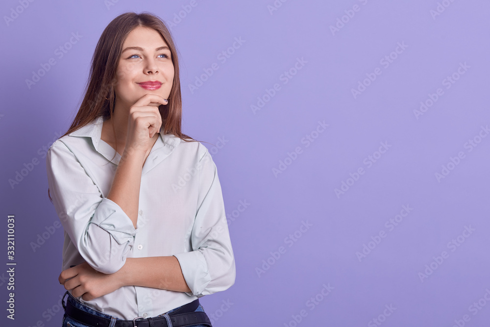 Fascinating blond business woman wearing white elegant blouse, looking aside with pencive facial expression, posing isoalted over lilac background. Copy space for adverisment or promotional text. Fascinating blond business woman wearing white elegant blouse, looking aside with pencive facial expression, posing isoalted over lilac background. Copy space for adverisment or promotional text.
