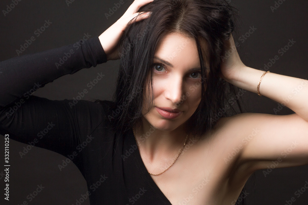 portrait of a brunette on a dark gray studio background in a black dress portrait of a brunette on a dark gray studio background in a black dress
