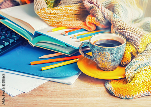 A cup of coffee, a knitted blanket and color pencils, selective focus..	 photo