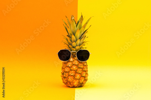 Pineapple with sunglasses on a orange and yellow background