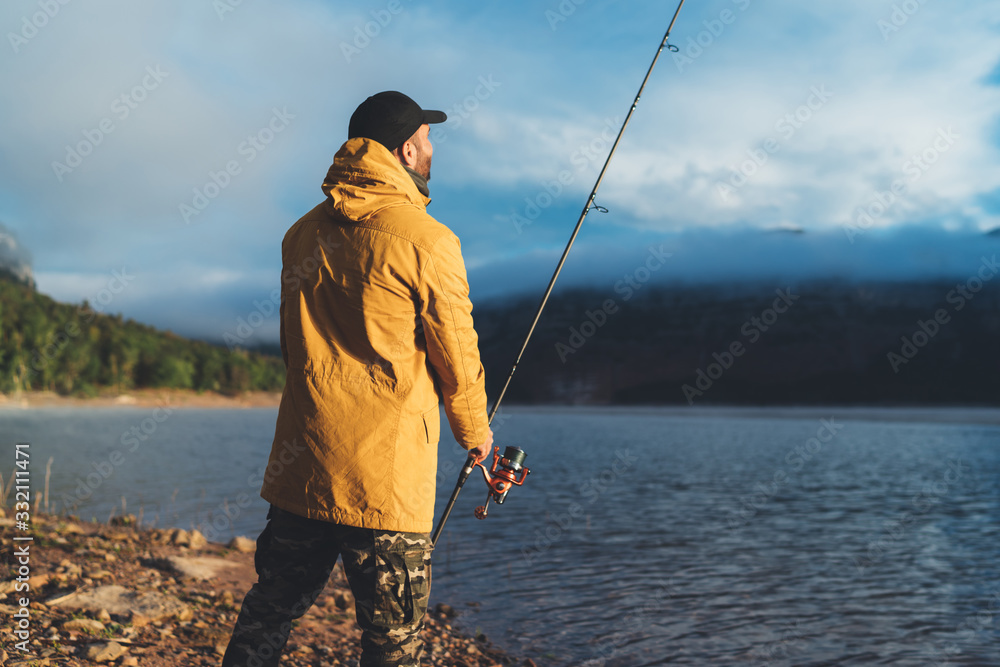 Obraz premium fishery concept, fisherman enjoy hobby sport with fishing rod on evening lake, person catch fish, holiday relaxation vacation