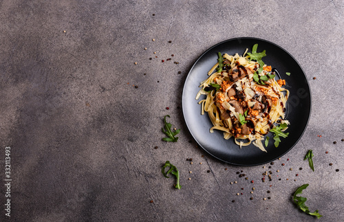 Bolognese pasta with mushrooms and arugula poured balsamic sauce on a grey background. Copy space for text.
