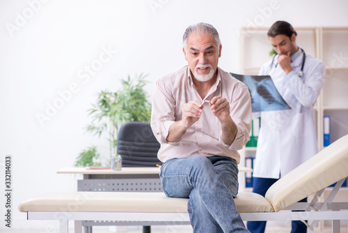 фотографія Young male doctor and old patient in antismoking concept