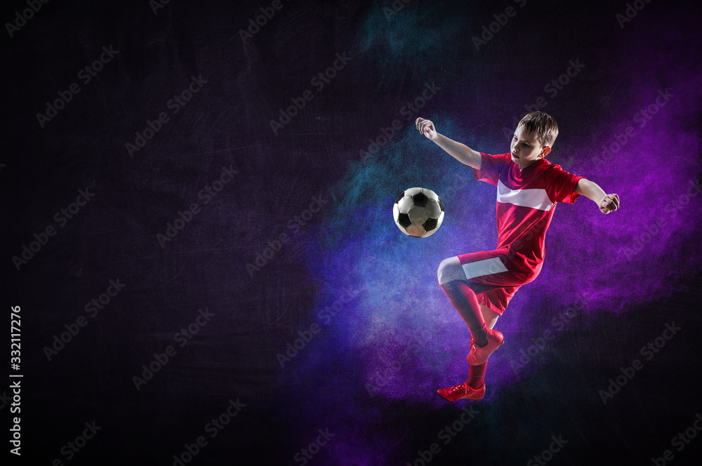 Boy playing soccer hitting the ball