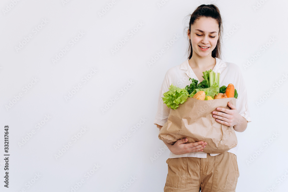 Hand with an eco paper bag with vegetables.Young hipster lifestyle girl holding paper bag with vegetables. Zero waste food shopping. eco natural concept Hand with an eco paper bag with vegetables.Young hipster lifestyle girl holding paper bag with vegetables. Zero waste food shopping. eco natural concept