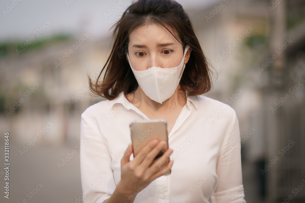 Shocked woman wearing protective mask corona virus (covid-19) use smart phone, worried about the news of the corona virus. Shocked woman wearing protective mask corona virus (covid-19) use smart phone, worried about the news of the corona virus.
