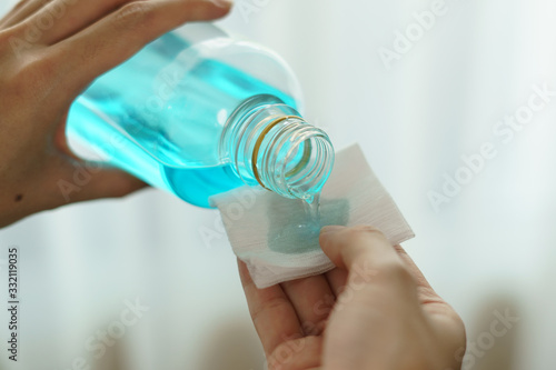 Pouring ethyl alcohol from bottle  into a cotton piece for corona virus or Covid-19 protection. photo