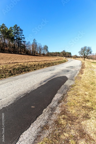 Old asphalt road near field. Czech landscape. Country road near the forest. Spring morning on country road.