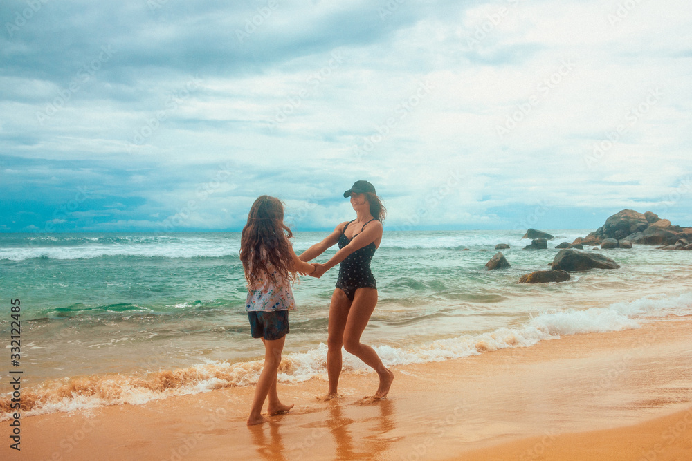 family relationship, mother with daughter are walking on the beach and smiling together. vacation concept, free space	
