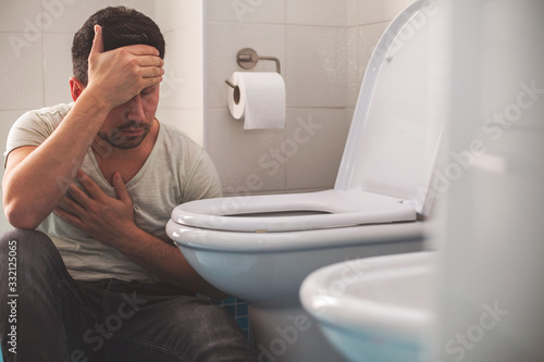 Fotografija Man feeling bad putting his head in toillet and vomiting.