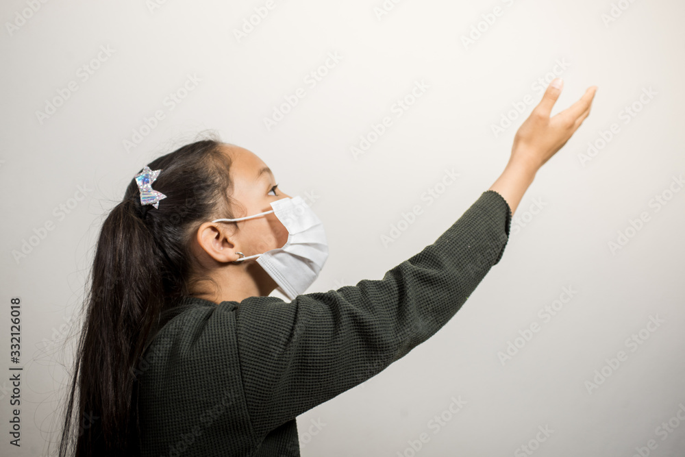 Little girl with medical mask looking up hoping that everything will turn out well. Girl rests her head on her hands during the coronavirus quarantine at home. Little girl with medical mask looking up hoping that everything will turn out well. Girl rests her head on her hands during the coronavirus quarantine at home.