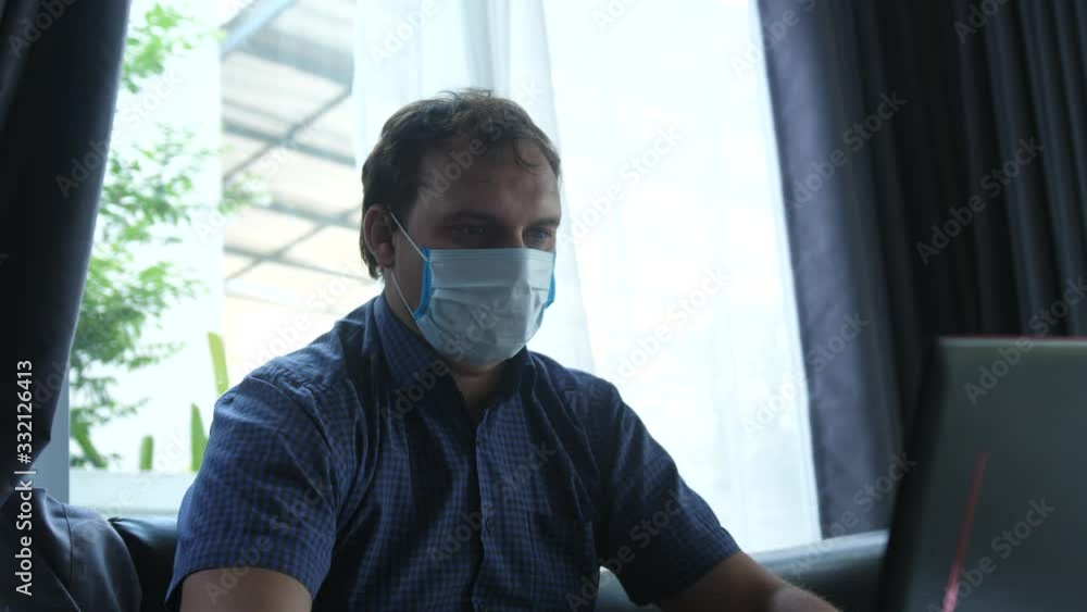 Man works from home in quarantine wearing a face mask Man works from home in quarantine wearing a face mask