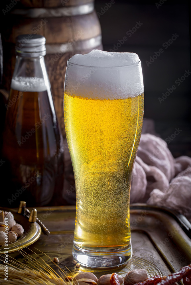 Light frothing beer in a glass, on an old background. Light frothing beer in a glass, on an old background.