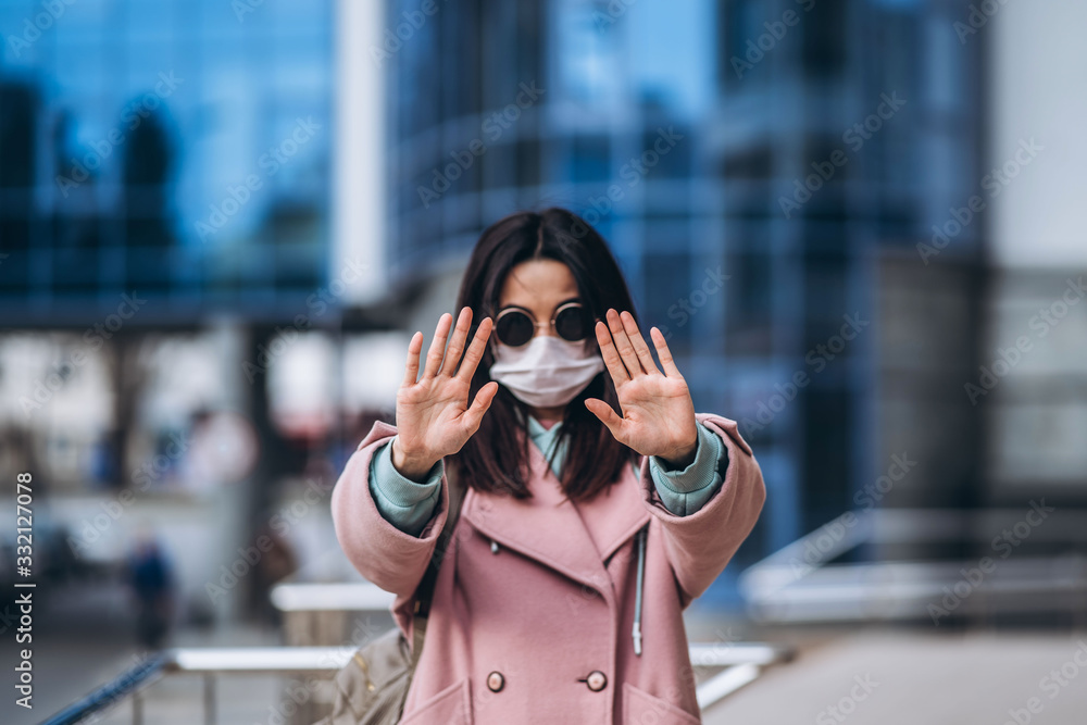 Female in medical mask outdoors show stop sign by her hands for social safe distance to prevent virus infection. Coronavirus, COVID-19, virus, desease, epidemic, pandemic, quarantine concept. Female in medical mask outdoors show stop sign by her hands for social safe distance to prevent virus infection. Coronavirus, COVID-19, virus, desease, epidemic, pandemic, quarantine concept.