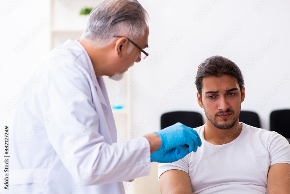 Leg injured man visiting old doctor in first aid concept Leg injured man visiting old doctor in first aid concept