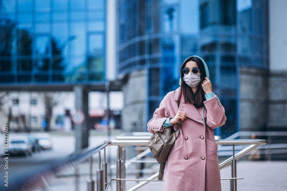 Fototapeta premium Female in medical protective mask outdoors in the empty city. Health protection and prevention of virus outbreak, coronavirus, COVID-19, epidemic and pandemic, quarantine concept