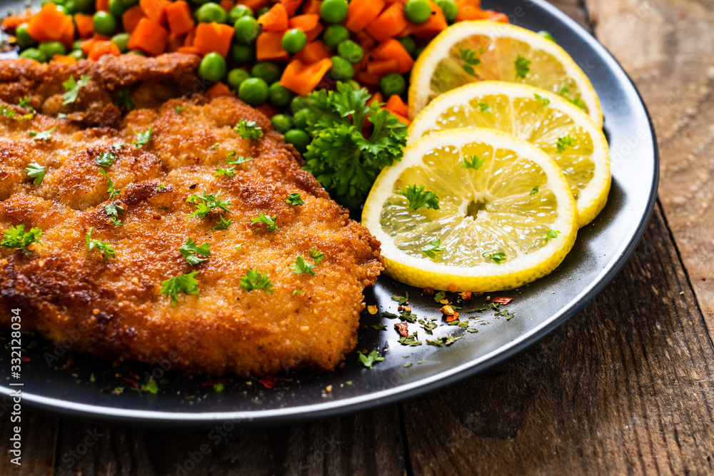 Schnitzel with boiled carrot and peas on wooden background Schnitzel with boiled carrot and peas on wooden background