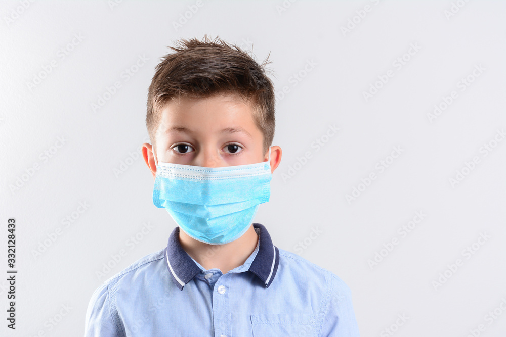 Front view, Closeup with the face of a child wearing medical or surgical mask to Avoid close contact with sick people. Isolated on white background. Boy in a medical mask Front view, Closeup with the face of a child wearing medical or surgical mask to Avoid close contact with sick people. Isolated on white background. Boy in a medical mask