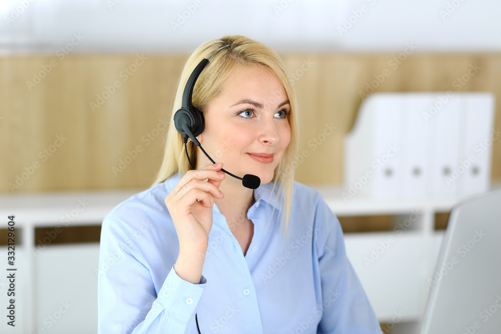 Call center. Blonde business woman sitting in headset at customer service office. Concept of telesales business or home office occupation Call center. Blonde business woman sitting in headset at customer service office. Concept of telesales business or home office occupation